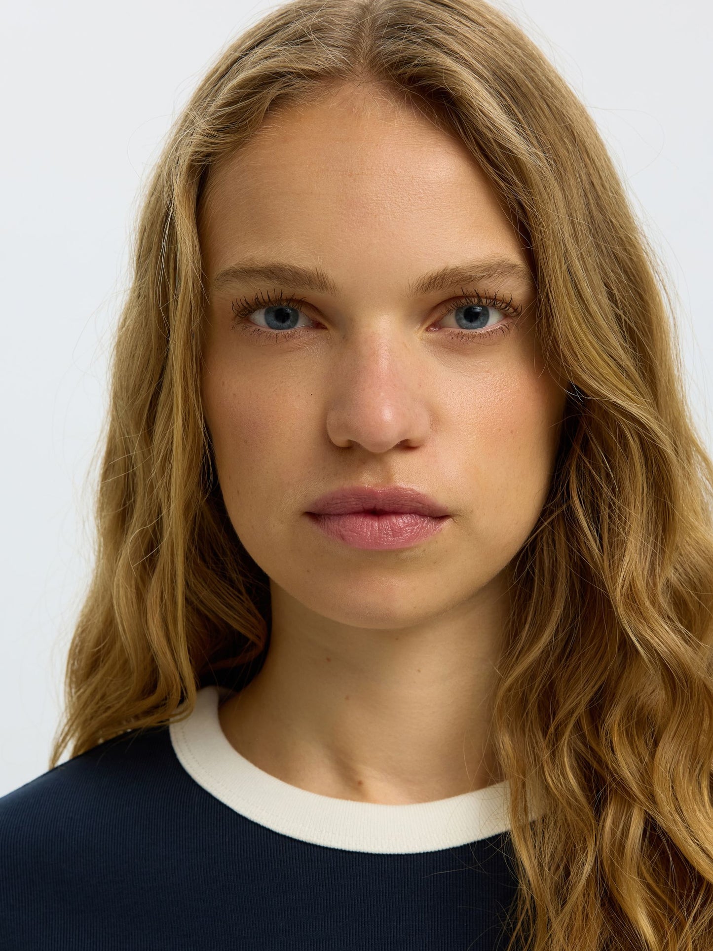 Close-up of a person with long blonde hair against a white background
