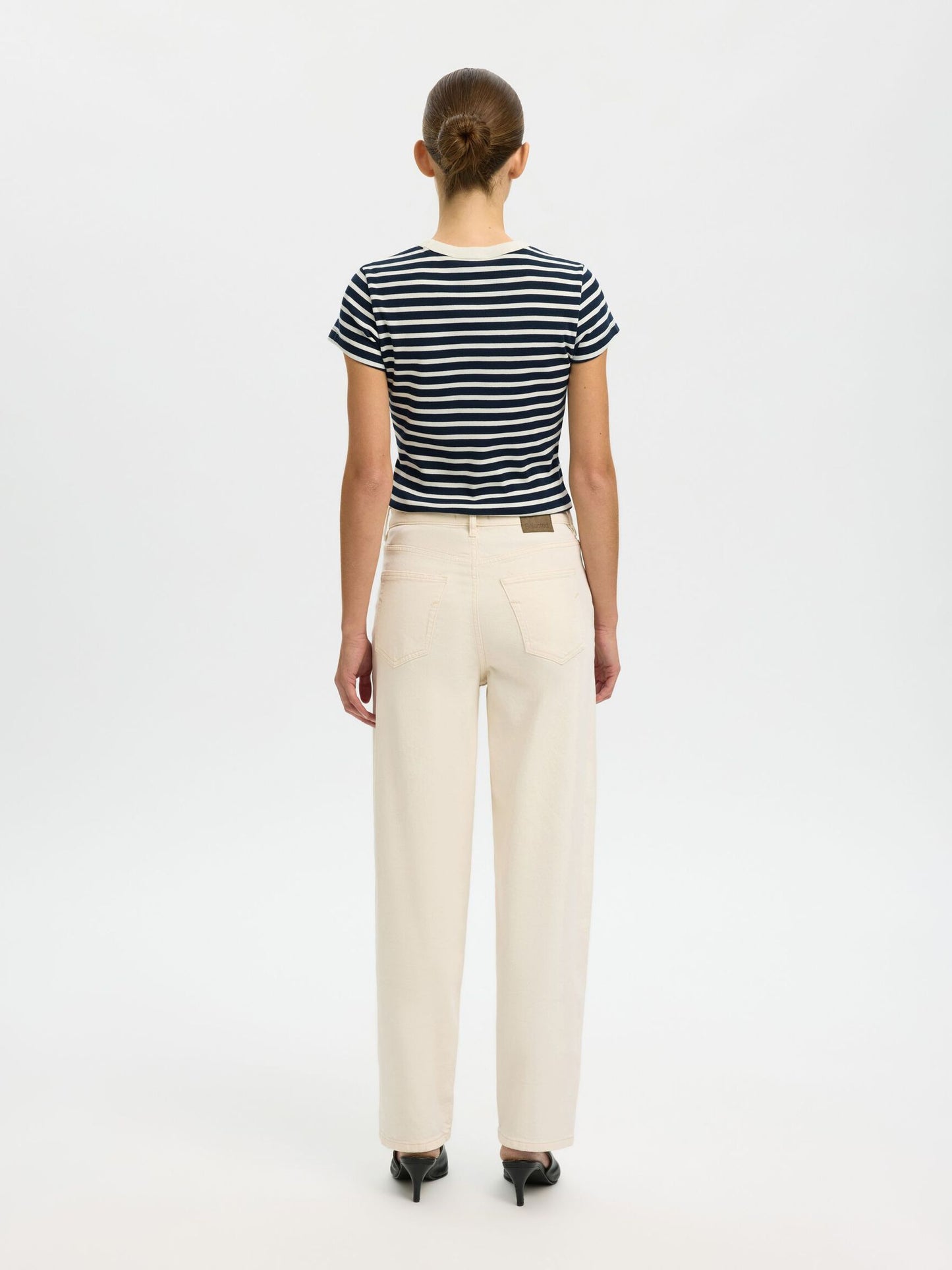 Person wearing a striped shirt and beige pants on a white background