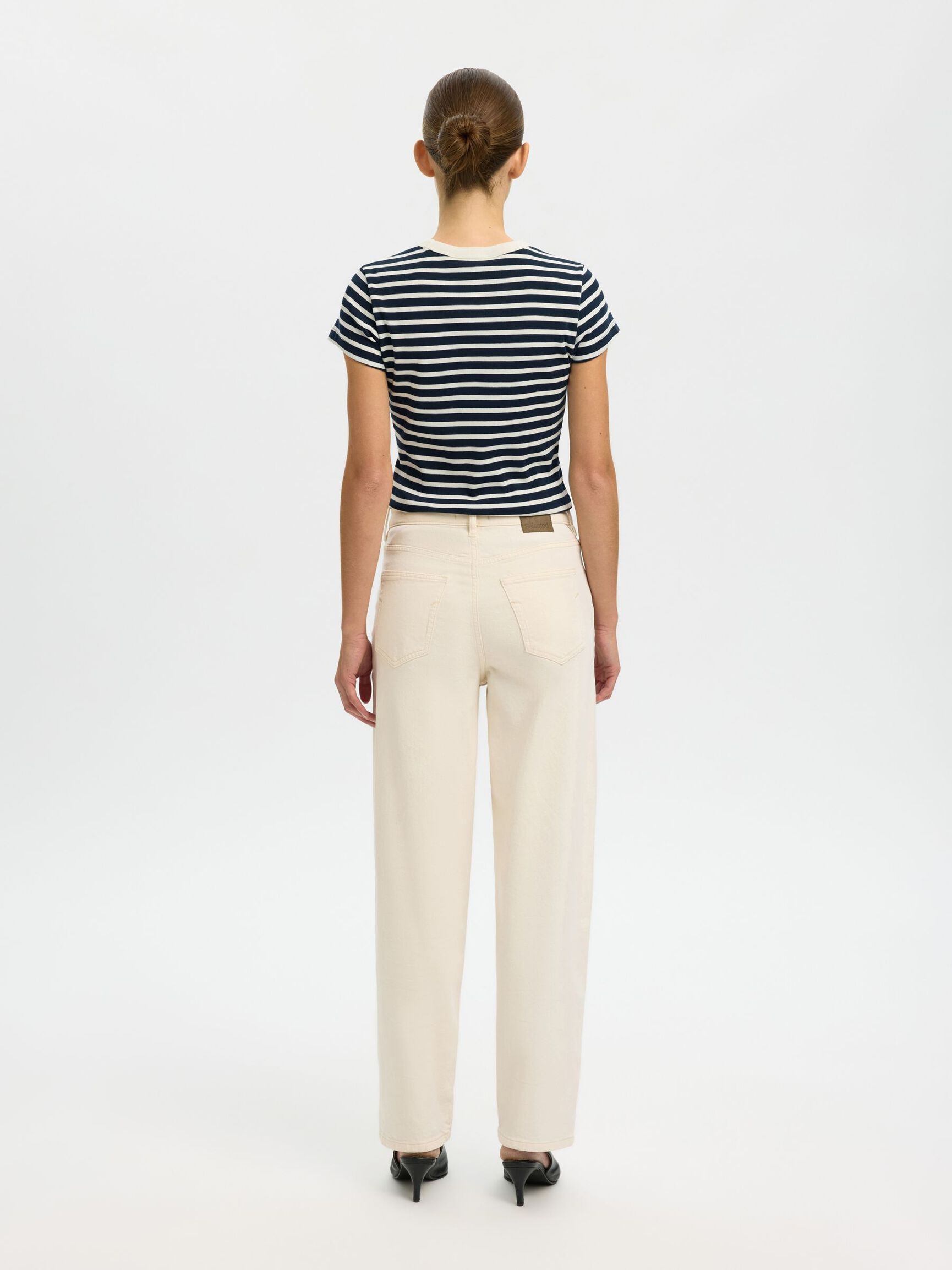 Person wearing a striped shirt and beige pants on a white background