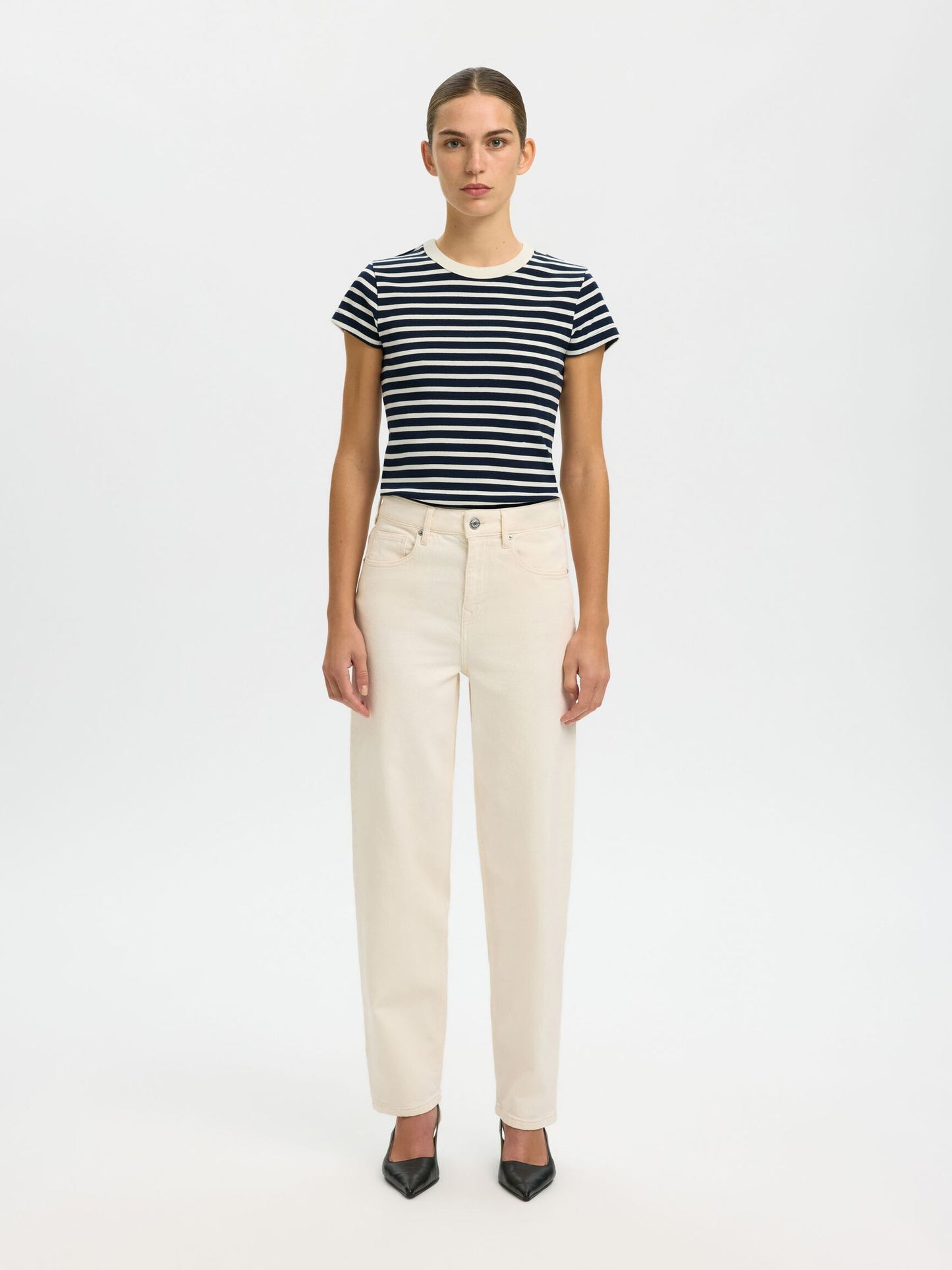 Woman wearing a striped shirt and beige pants on a white background