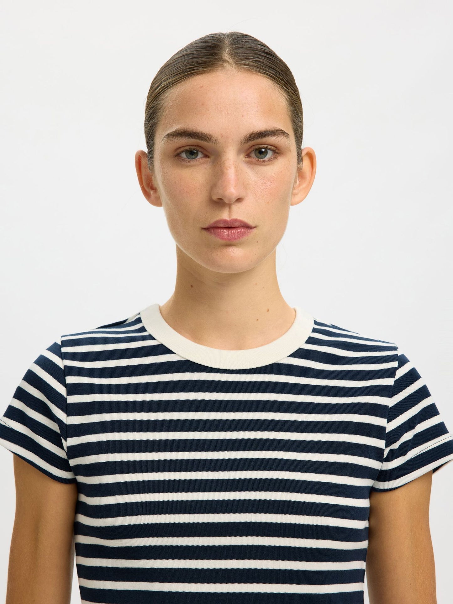 Person wearing a navy and white striped shirt against a plain background
