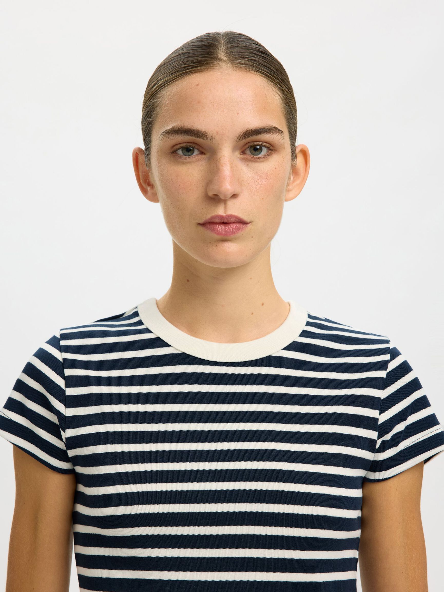 Person wearing a navy and white striped shirt against a plain background