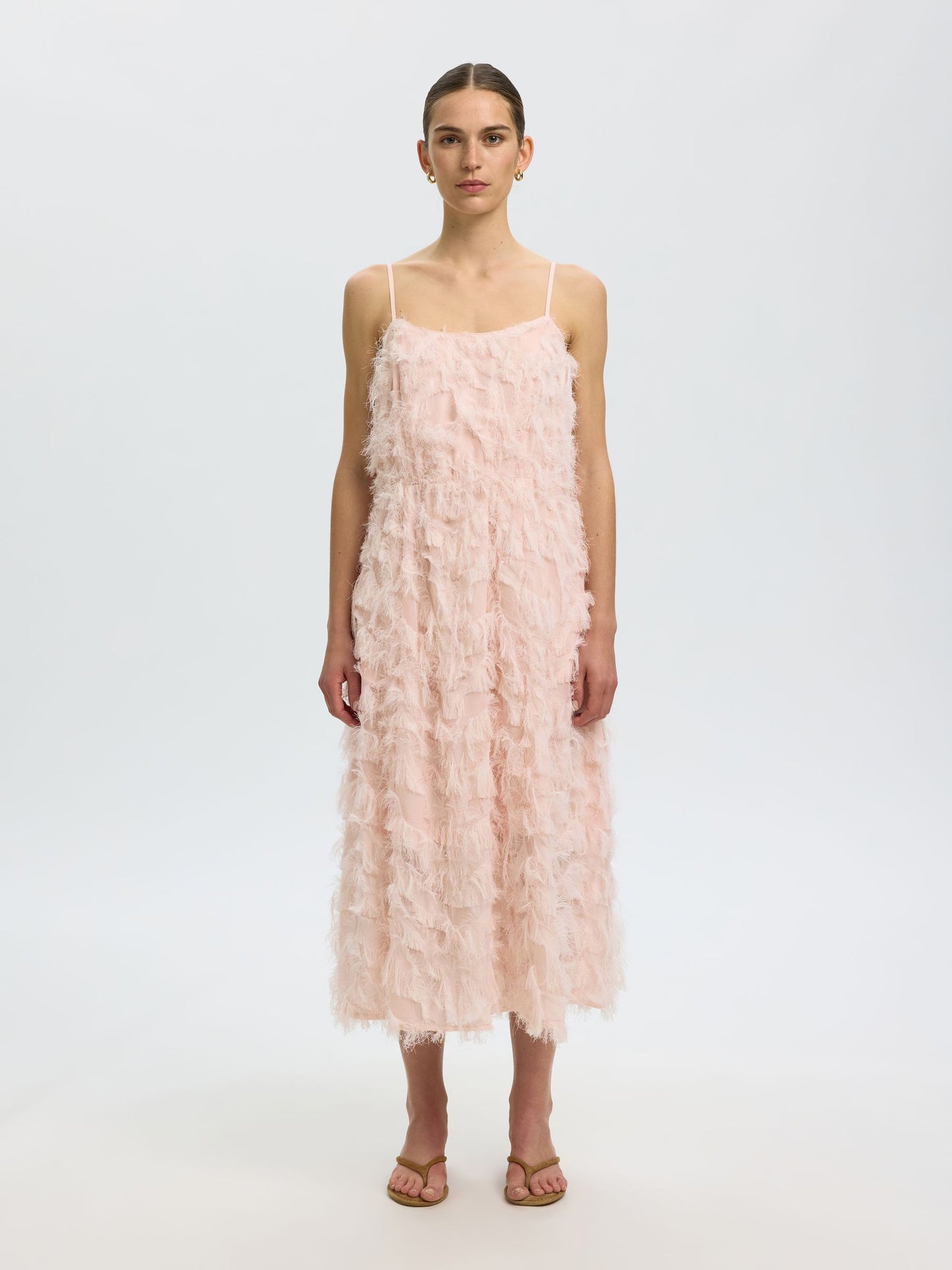 Woman wearing a pink ruffled dress on a white background
