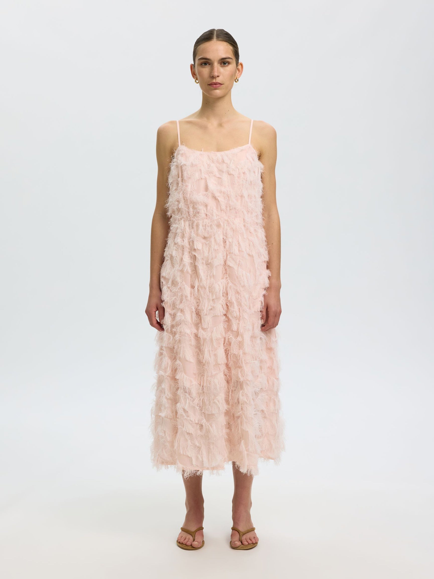 Woman wearing a pink ruffled dress on a white background