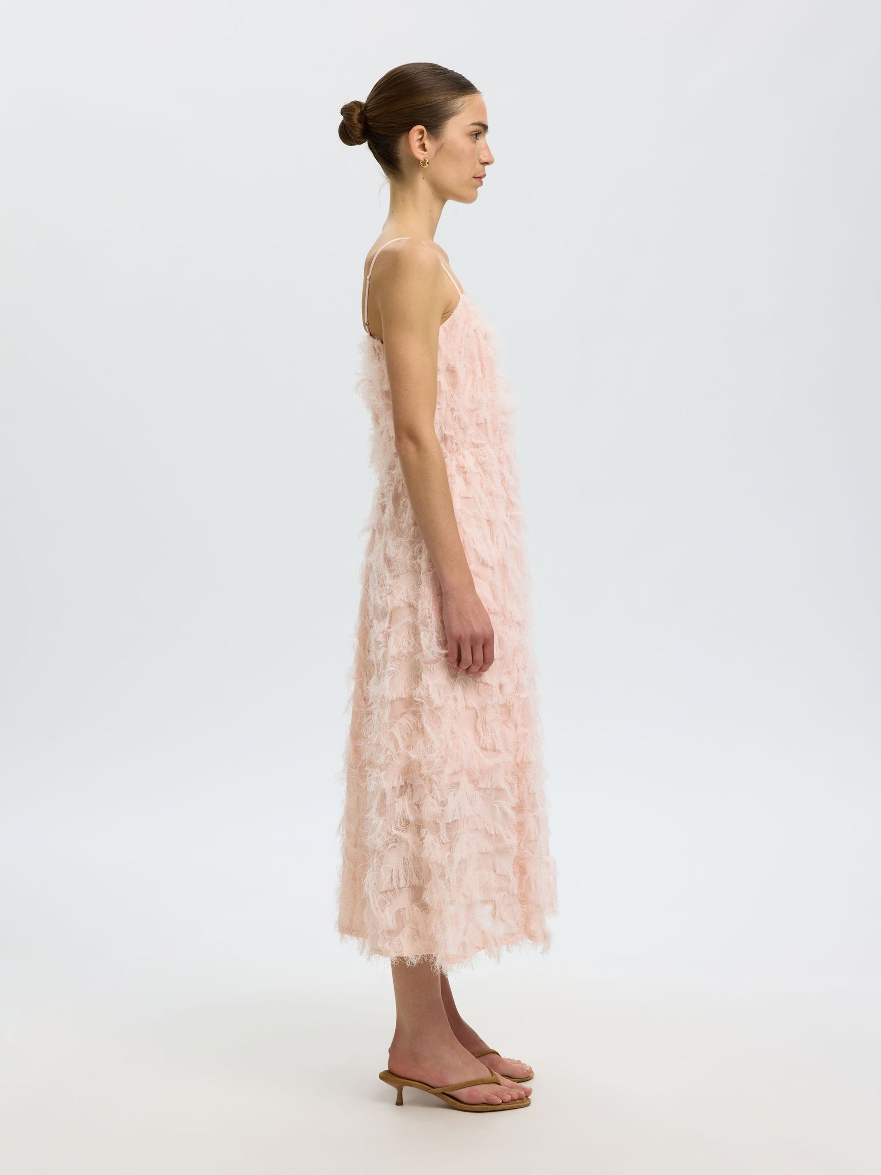 Woman wearing a light pink lace dress on a white background