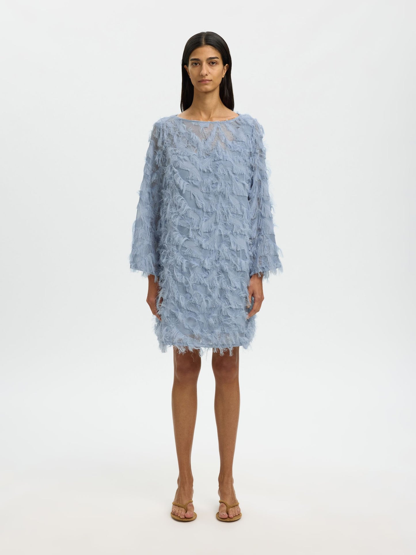 Woman wearing a light blue textured dress on a white background