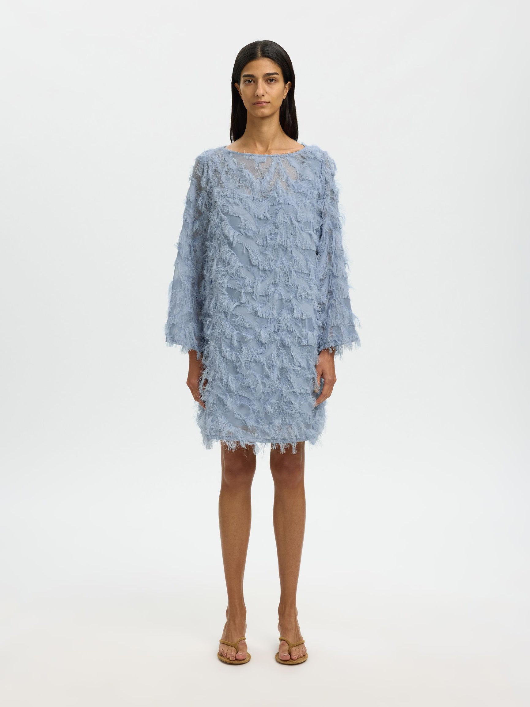 Woman wearing a light blue textured dress on a white background