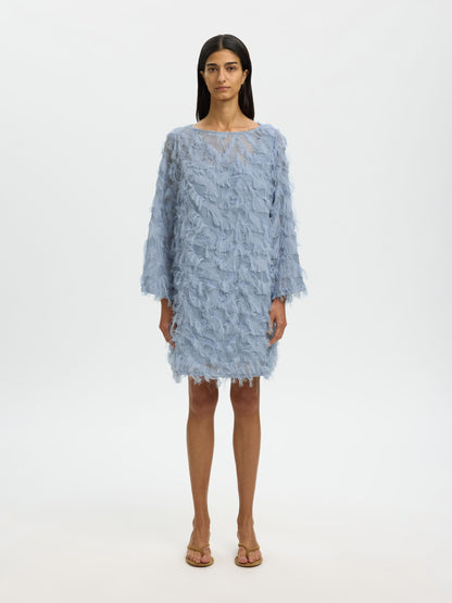 Woman wearing a light blue textured dress on a white background