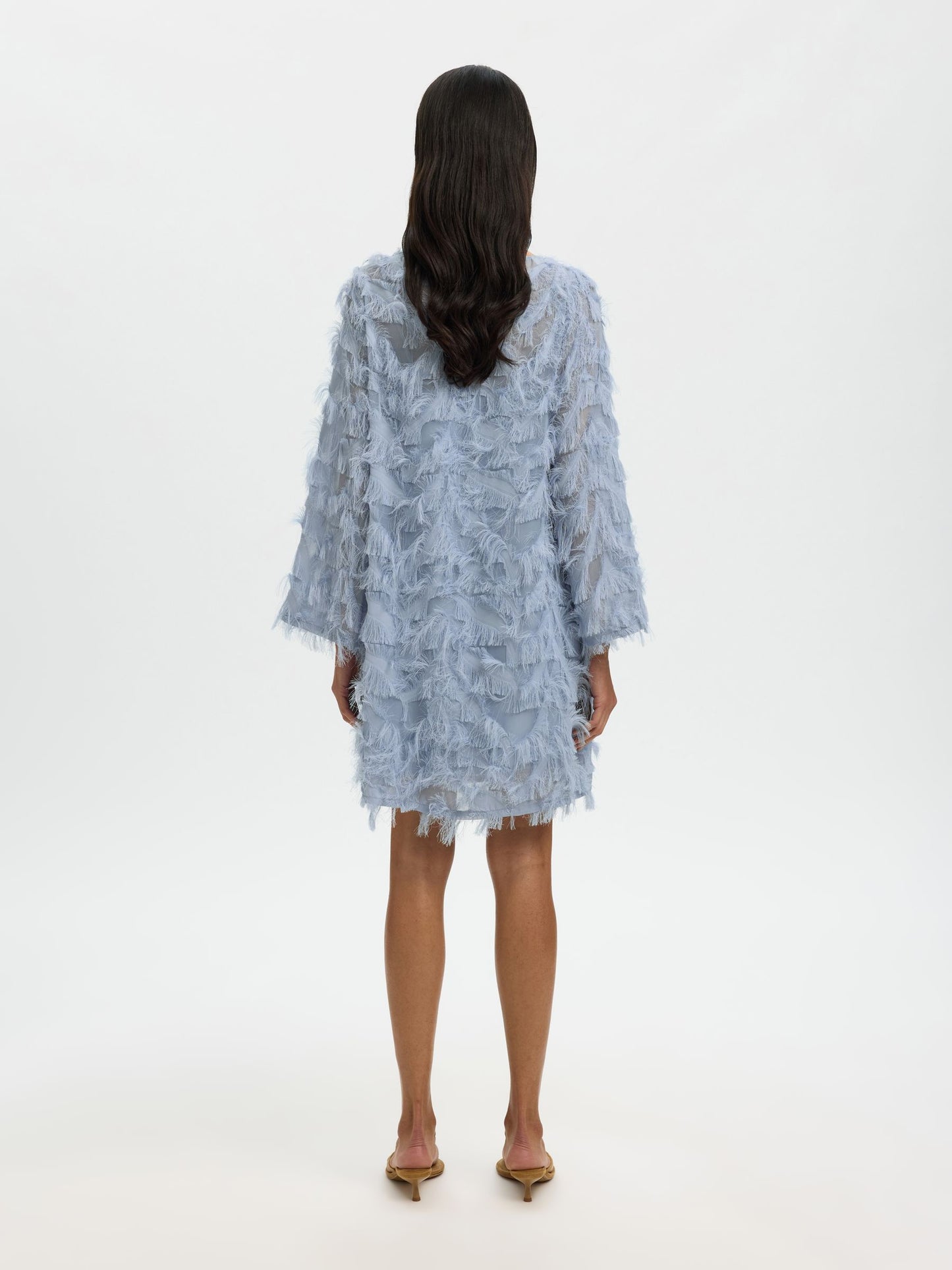 Woman wearing a light blue lace dress on a white background