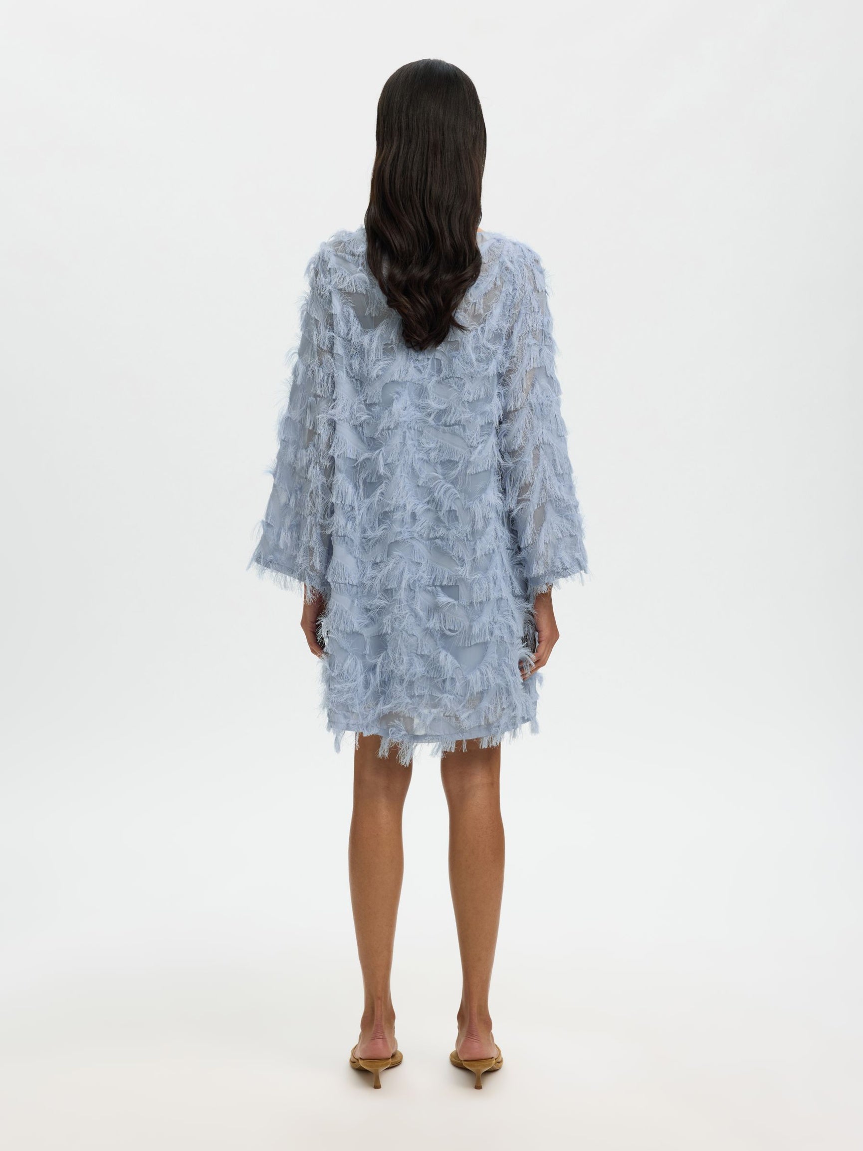 Woman wearing a light blue lace dress on a white background