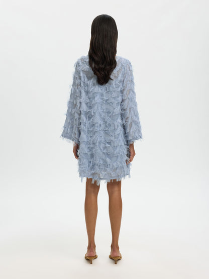 Woman wearing a light blue lace dress on a white background