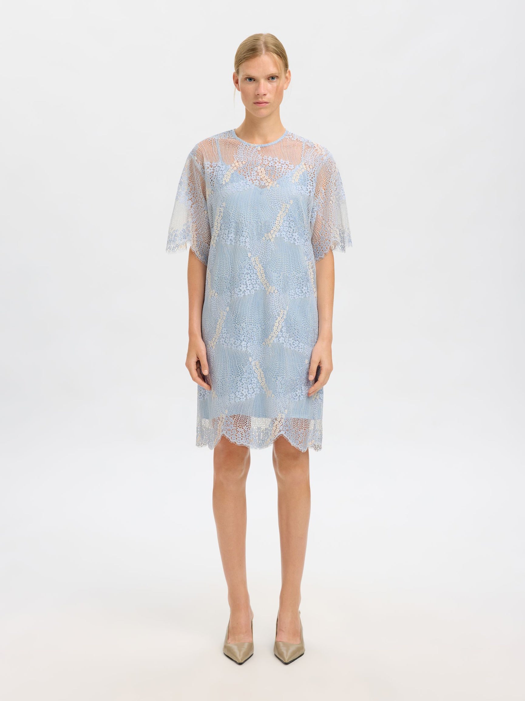 Woman wearing a light blue lace dress on a white background