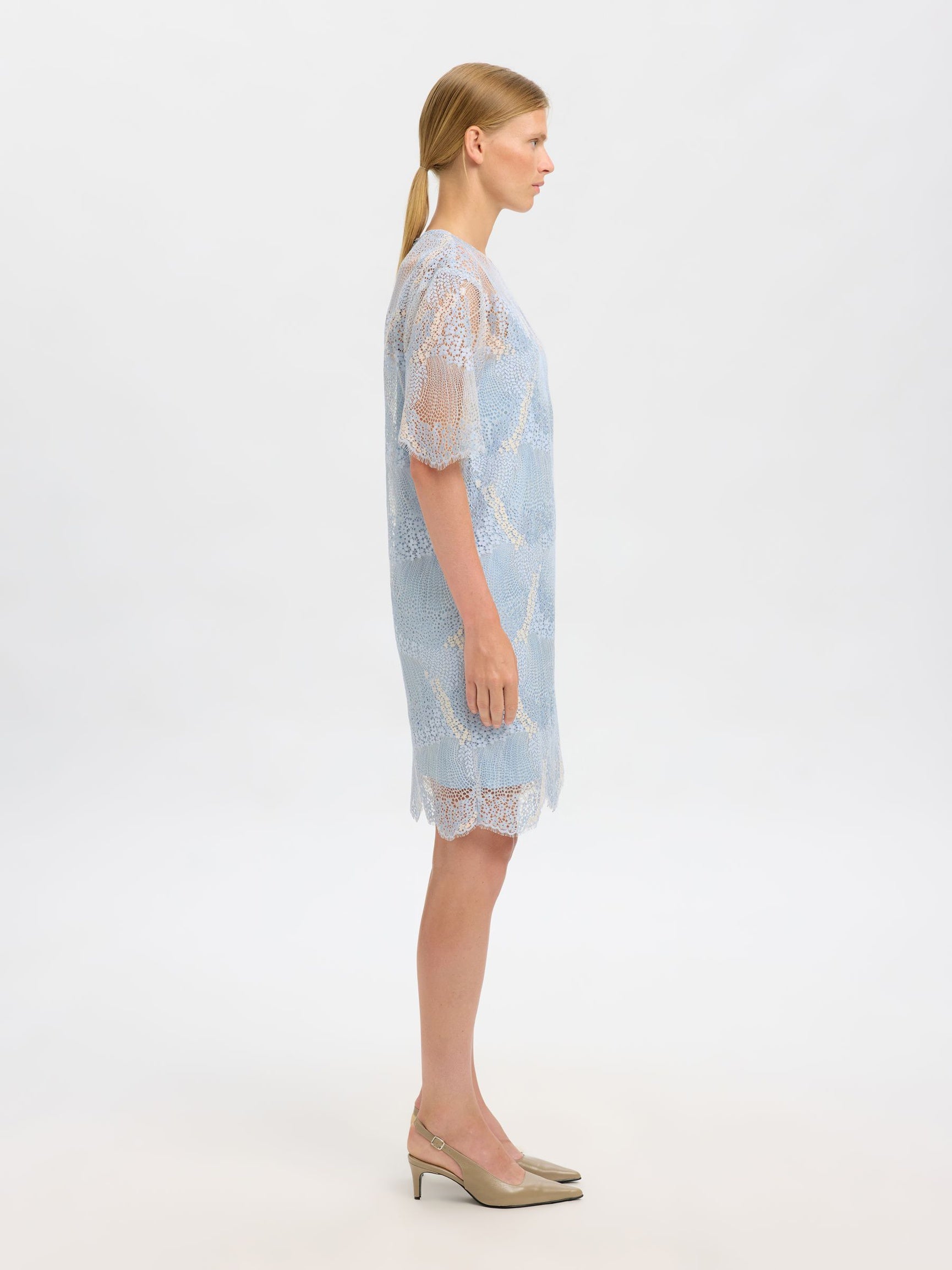 Woman wearing a light blue lace dress on a white background