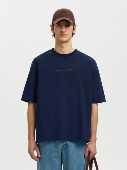 Person wearing a navy t-shirt with text and a brown cap on a light gray background