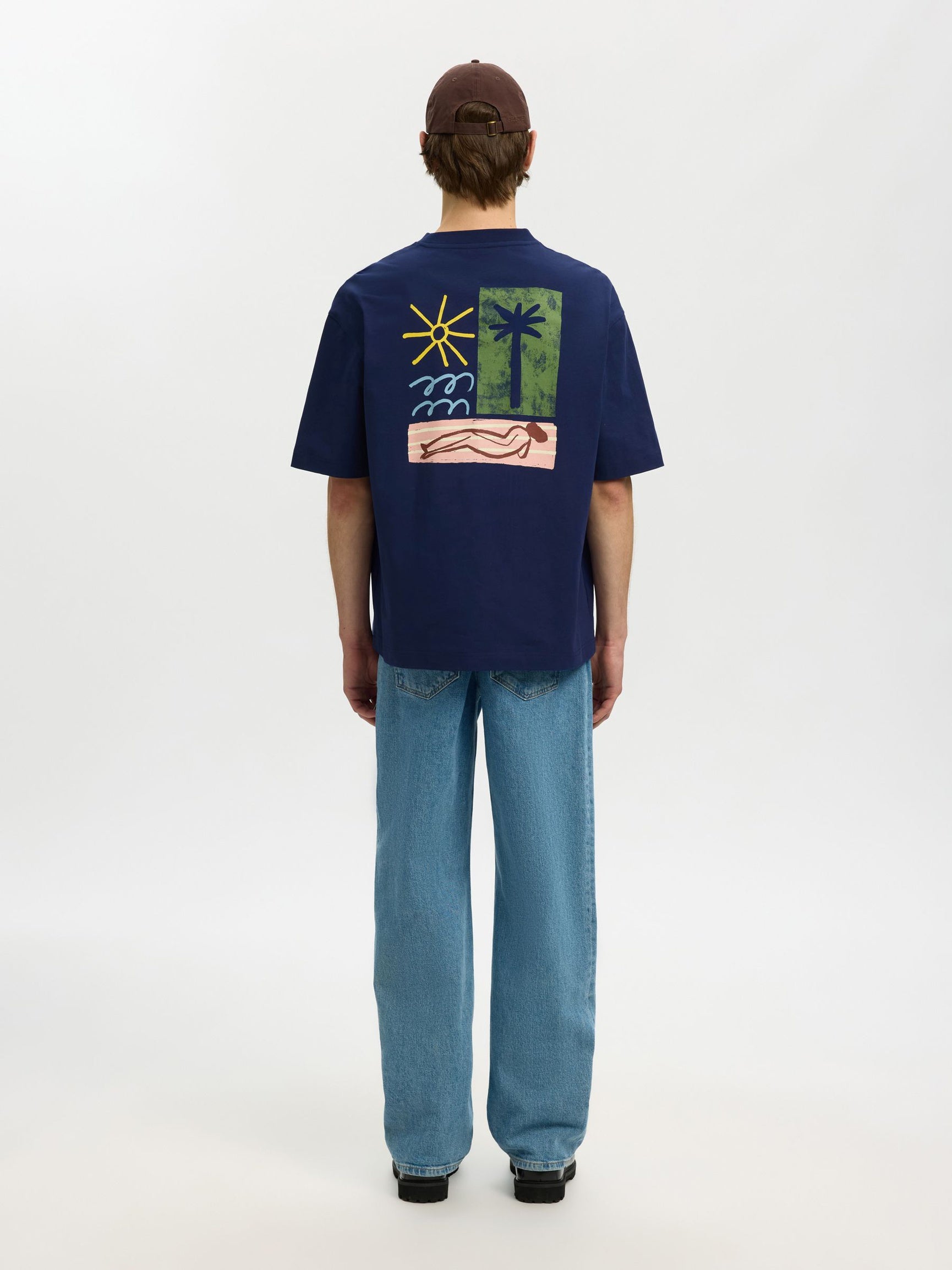 Person wearing a navy blue t-shirt with a colorful graphic on the back, standing against a white background.