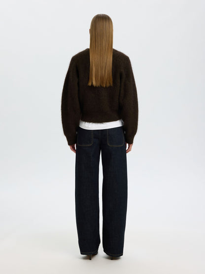 A model shown from the back wearing a dark brown fuzzy cropped sweater, dark wide-leg jeans, and a white undershirt, against a plain white studio background.