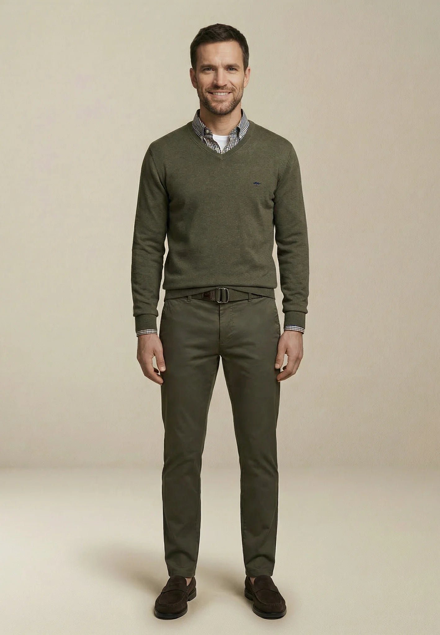 Man wearing a green sweater and pants on a beige background