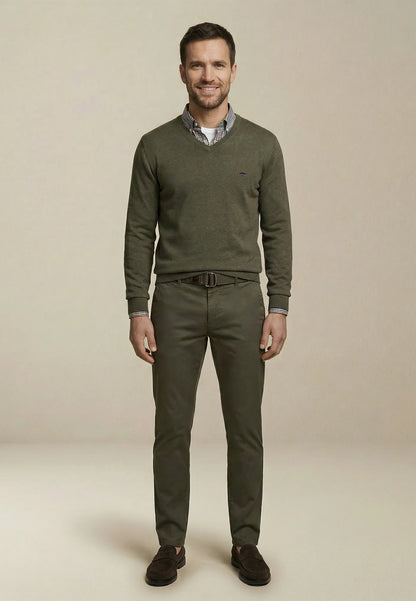 Man wearing a green sweater and pants on a beige background