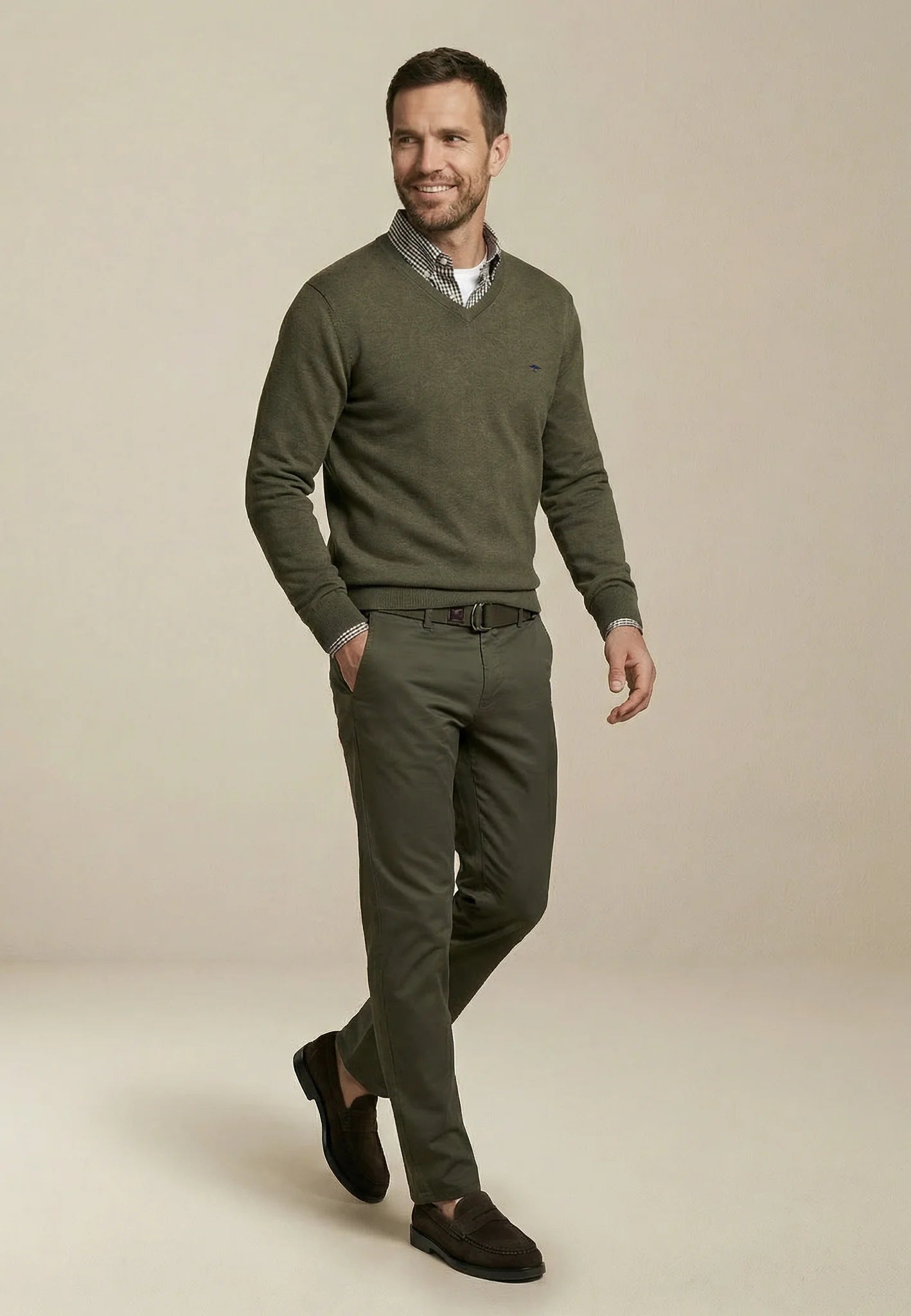 Man wearing a green sweater and pants on a beige background