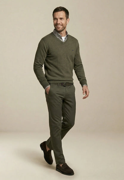 Man wearing a green sweater and pants on a beige background