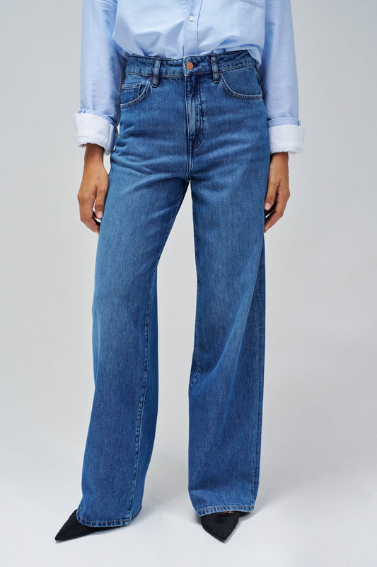 Person wearing blue jeans and a light blue shirt on a plain background.