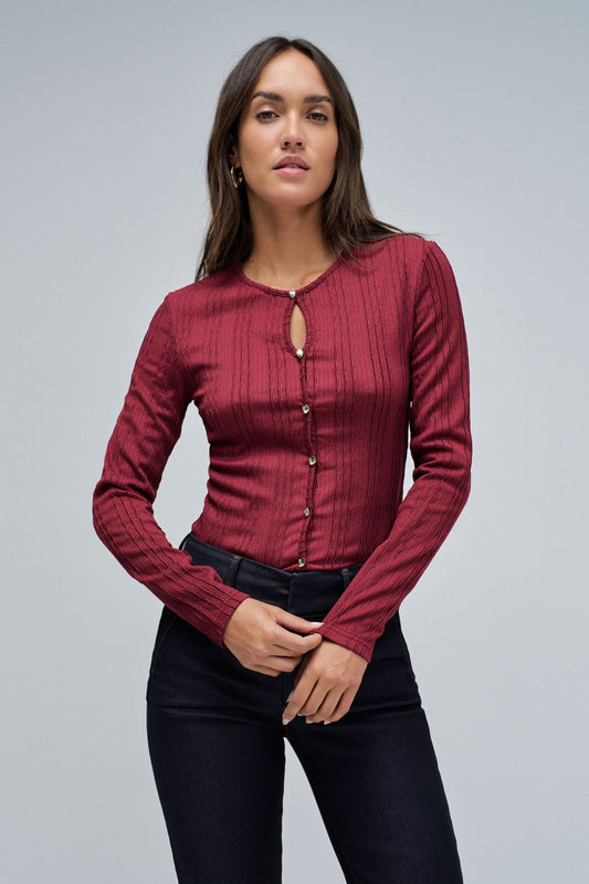 Woman wearing a red long-sleeve top with buttons on a gray background