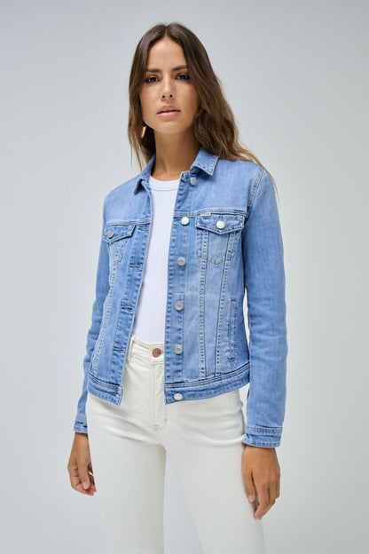 Woman wearing a blue denim jacket over a white shirt and pants on a gray background