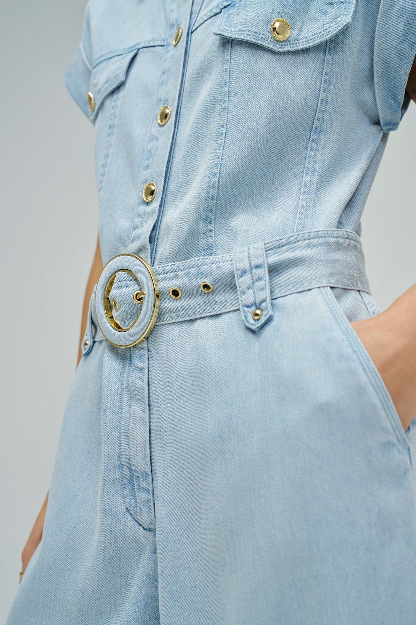 Light blue denim dress with a belt on a neutral background