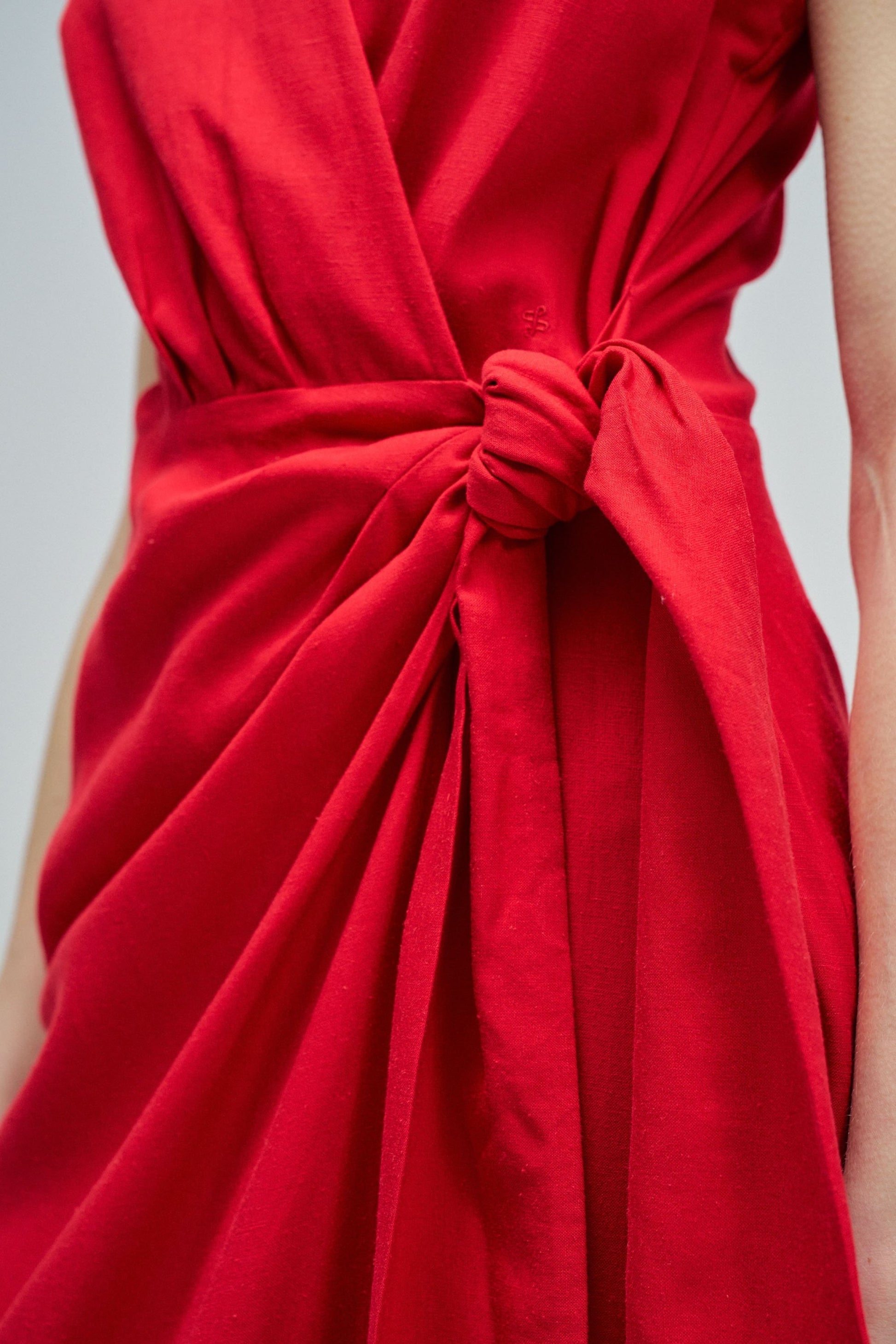 Red dress with a knot detail on a neutral background