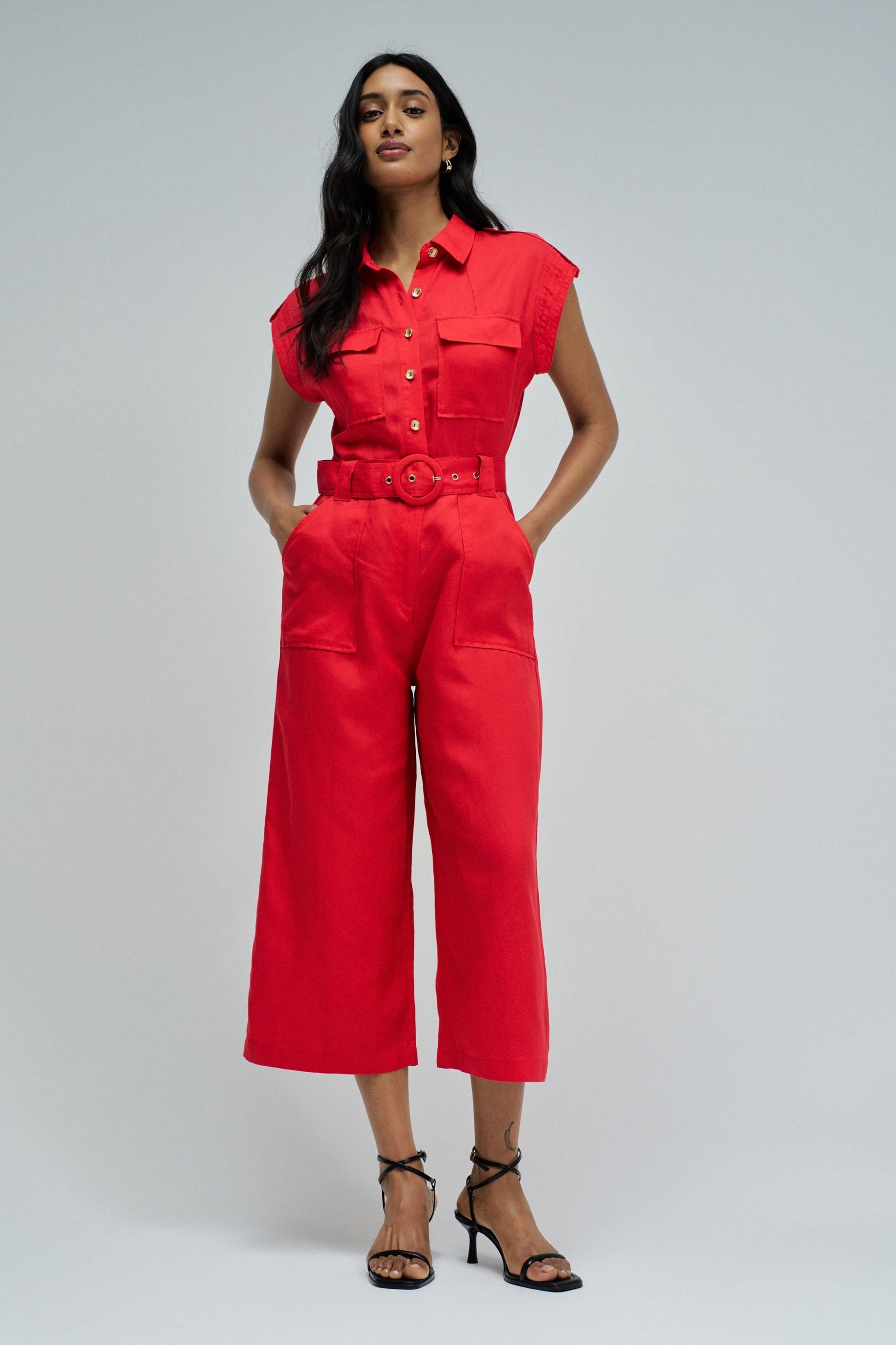 Woman wearing a red jumpsuit on a gray background