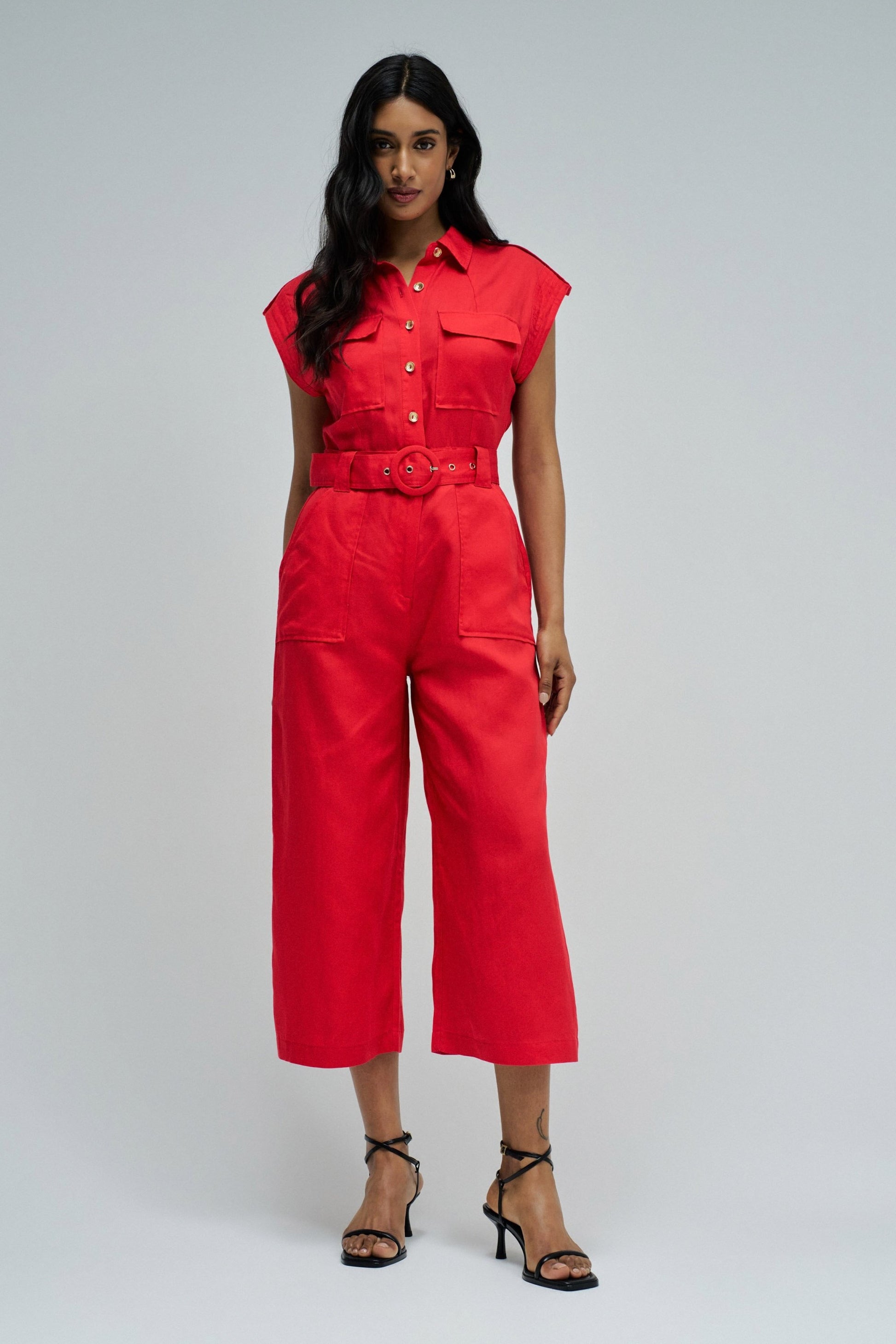 Woman wearing a red jumpsuit on a gray background