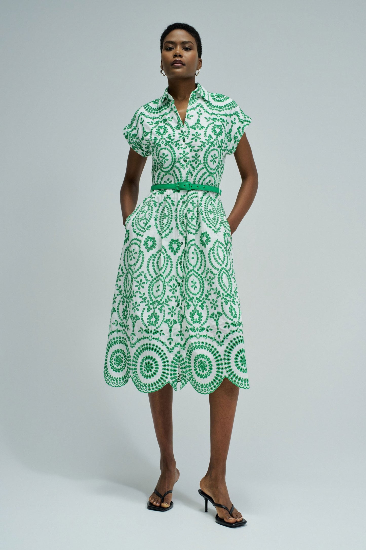 Woman wearing a green and white patterned dress on a plain background