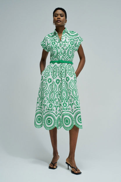 Woman wearing a green and white patterned dress on a plain background