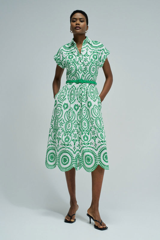 Woman wearing a green and white patterned dress on a plain background