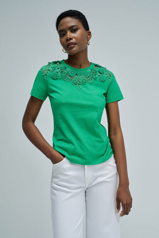 Woman wearing a green blouse with lace details on a gray background