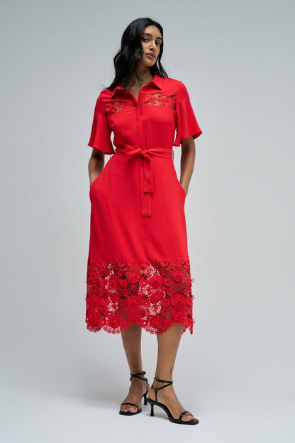 Woman wearing a red dress with lace details on a gray background