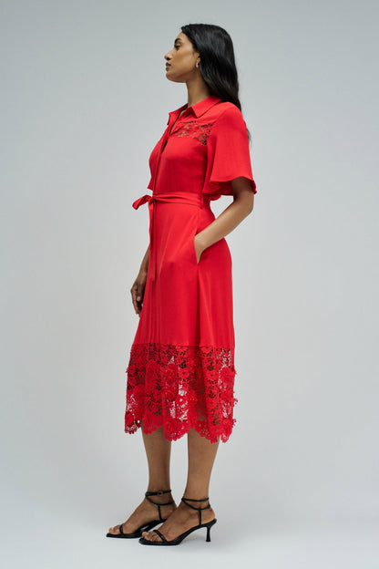Woman wearing a red dress with lace details on a white background