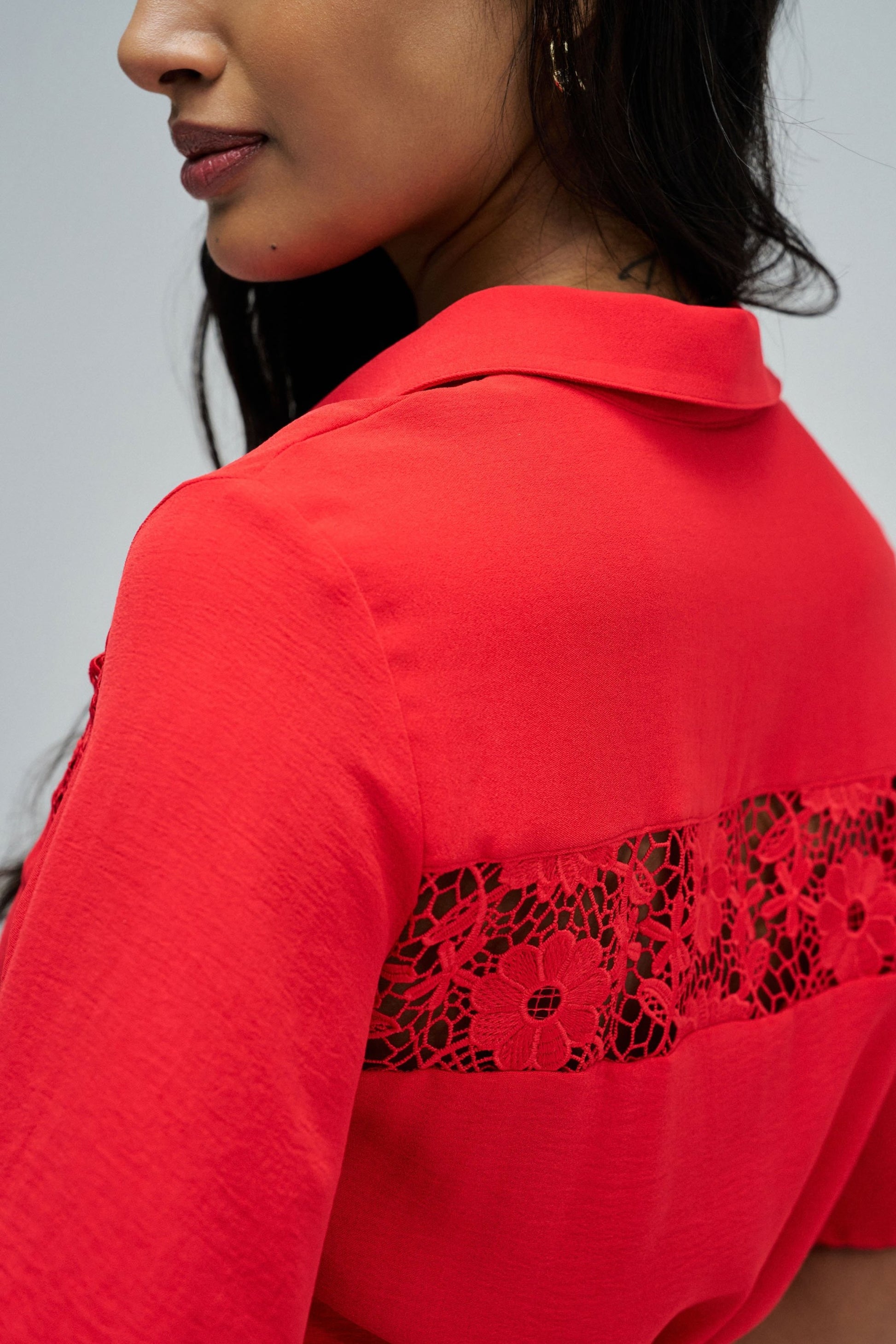 Red shirt with lace detailing on a plain background