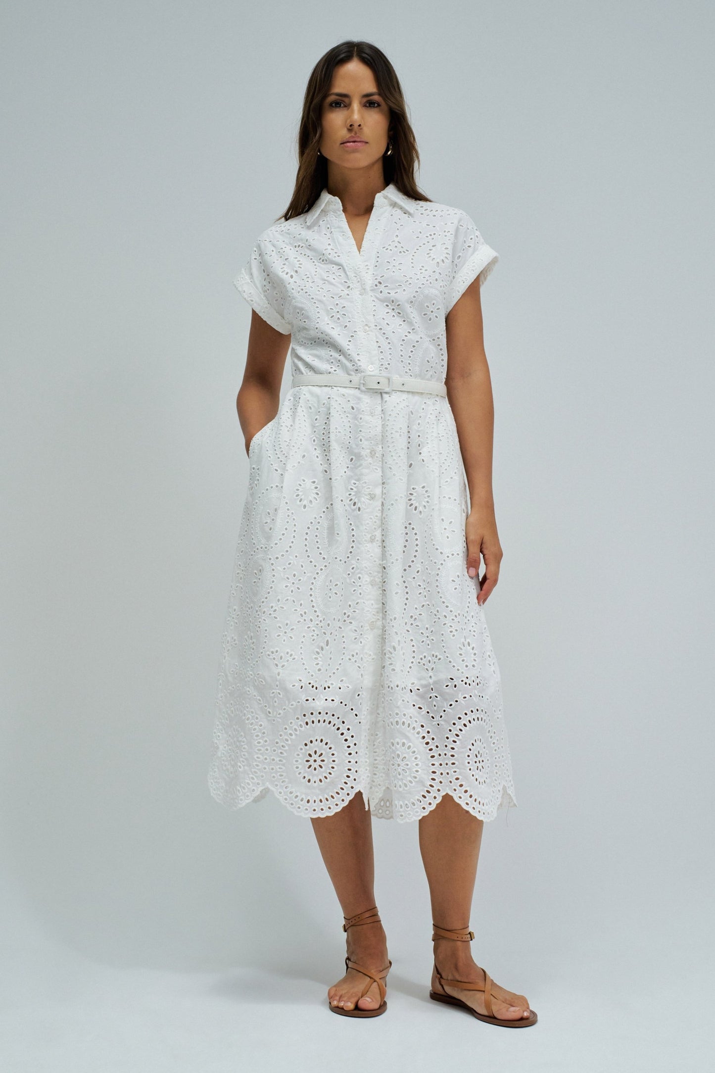 Woman wearing a white lace dress on a plain background