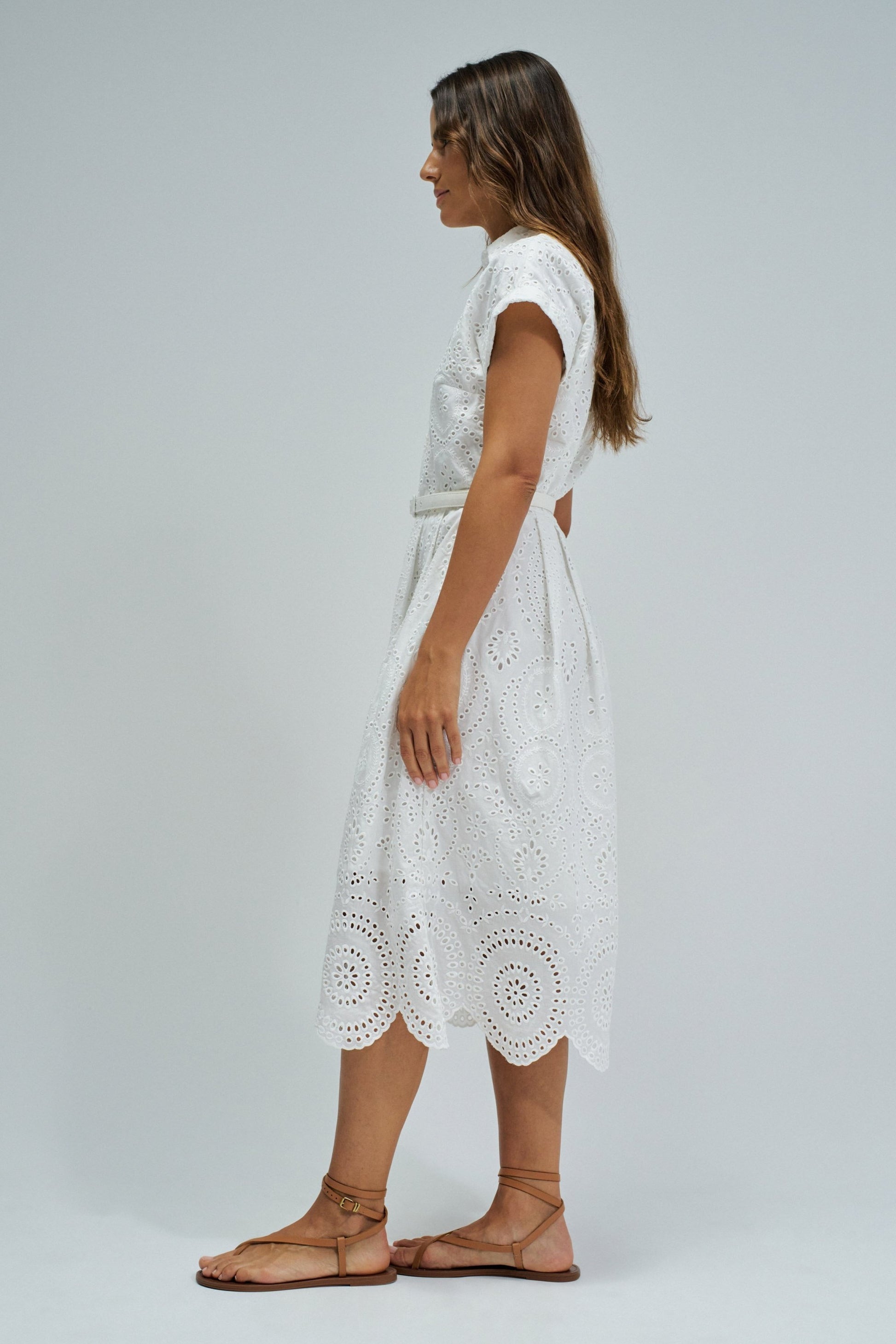 Woman wearing a white lace dress on a plain background