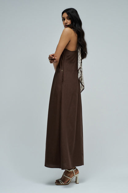 Woman wearing a long brown dress on a plain background