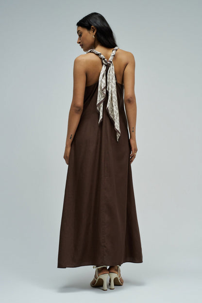 Woman wearing a brown dress with a scarf on a plain background