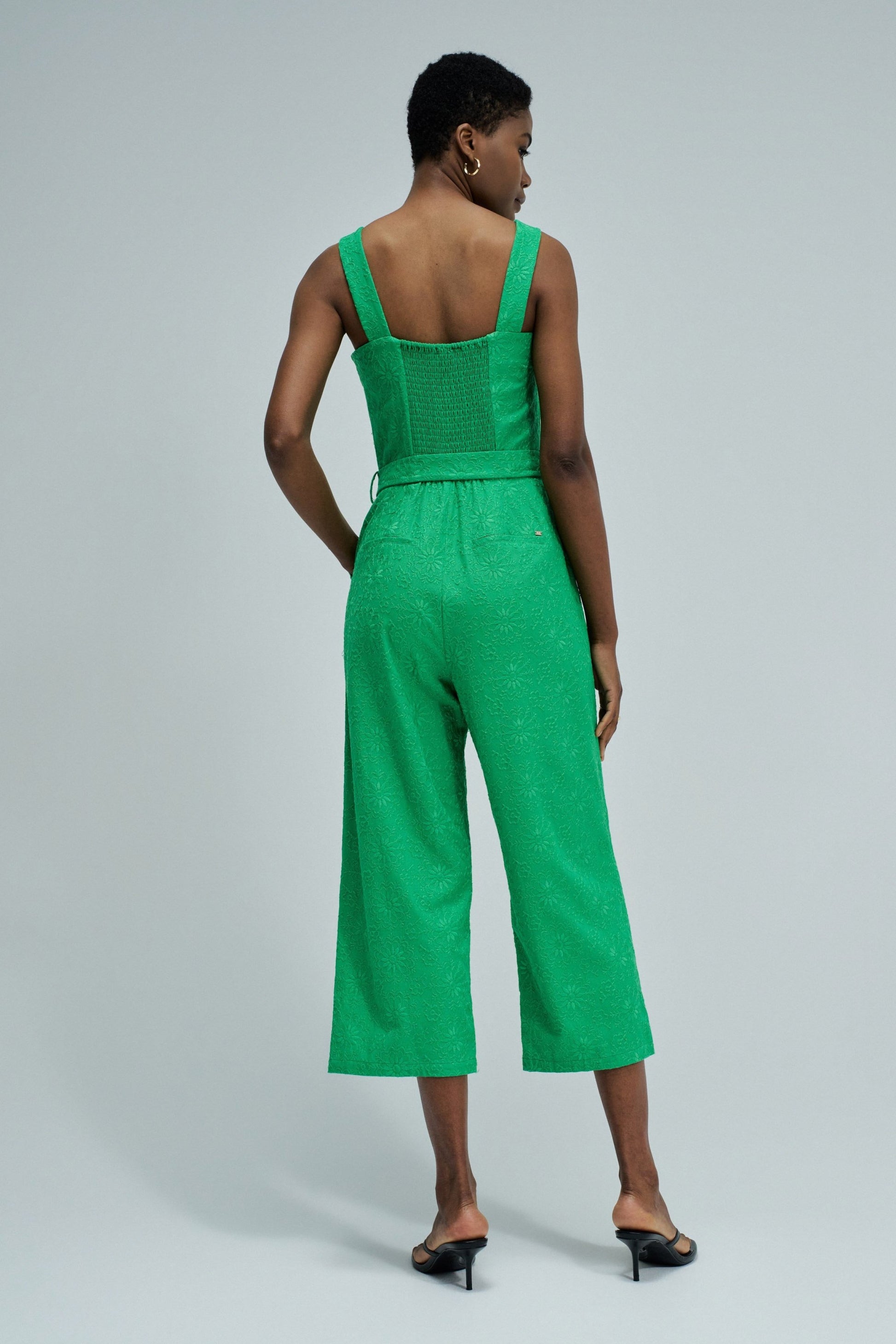 Woman wearing a green jumpsuit on a light gray background