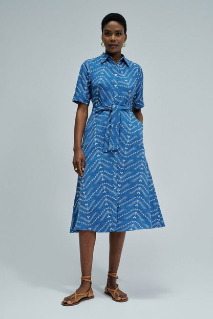 Woman wearing a blue patterned dress on a gray background