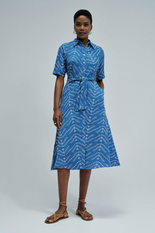 Woman wearing a blue patterned dress on a gray background