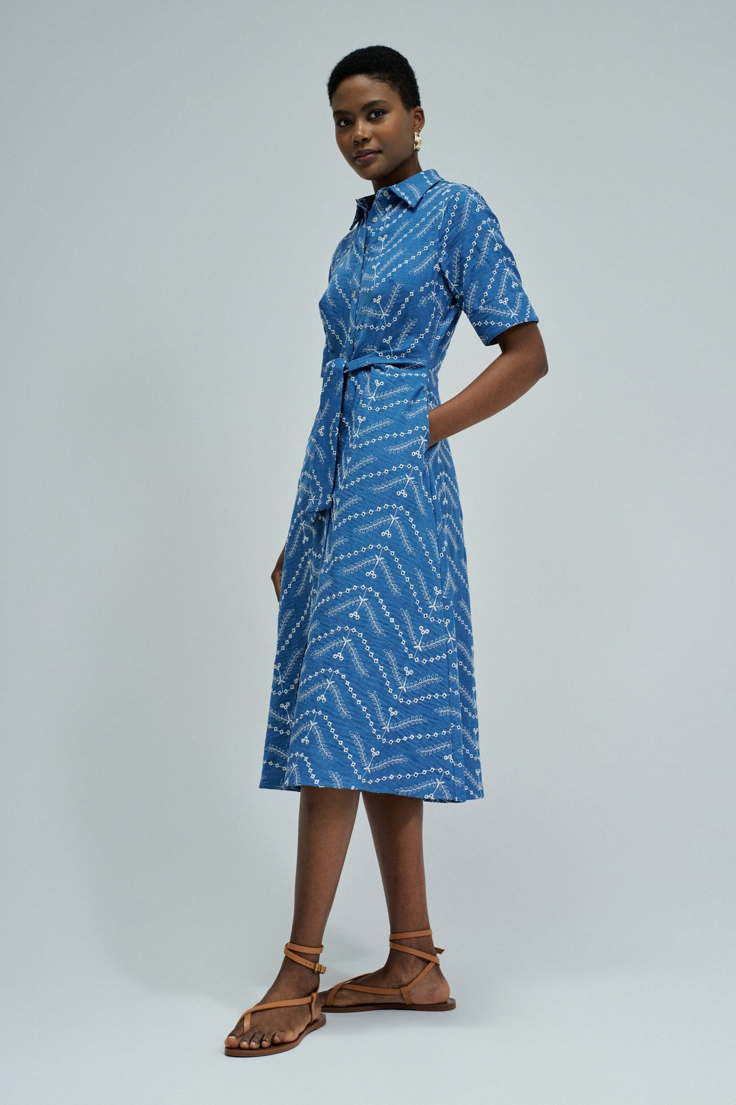 Woman wearing a blue patterned dress on a gray background