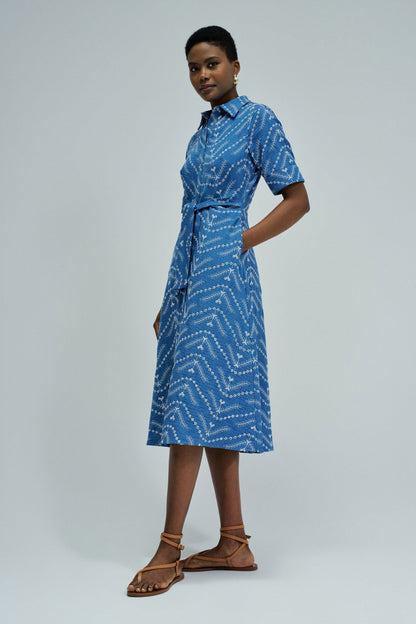Woman wearing a blue patterned dress on a gray background