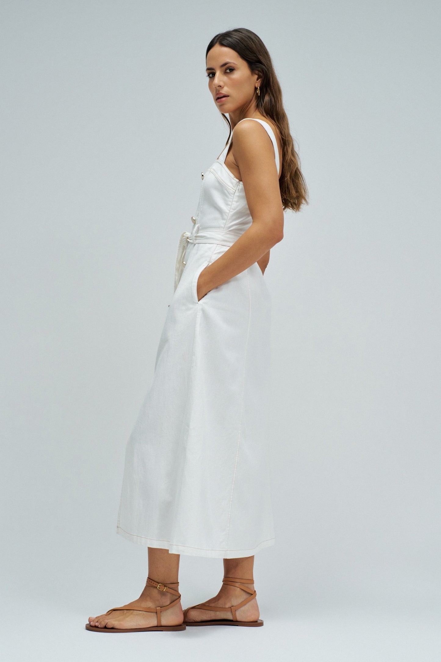 Woman wearing a white dress with a belt on a plain background