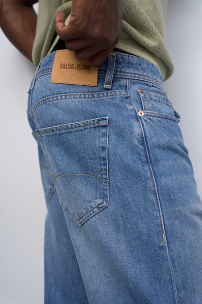 Close-up of blue jeans with a visible brand label on a white background
