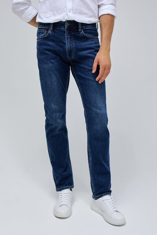 Person wearing blue jeans and white sneakers on a plain background